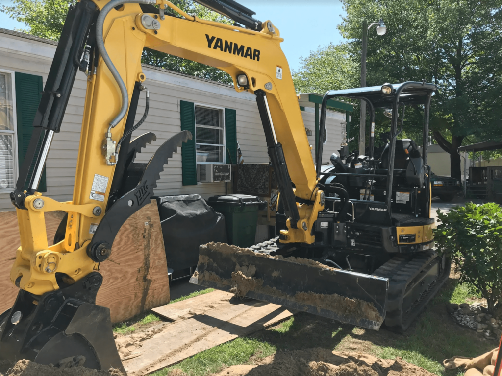 Excavator digging up section of broken pipe