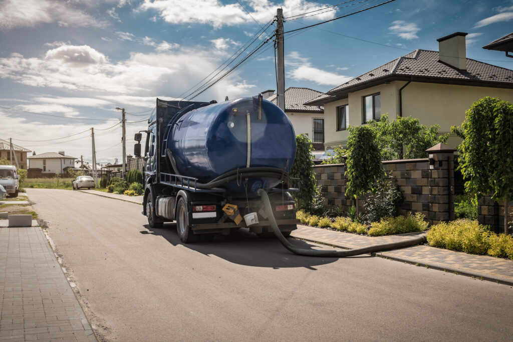 A septic truck parked outside a house that is used for septic tank pumping