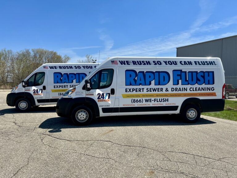 Two Rapid Flush drain cleaning vans parked next to each other in a parking lot.