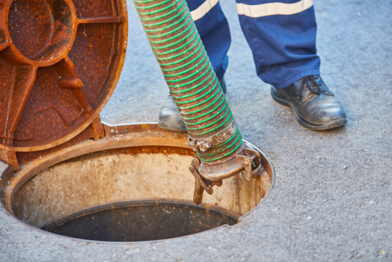 A close up view of a cleaning pipe being inserted into a septic tank.