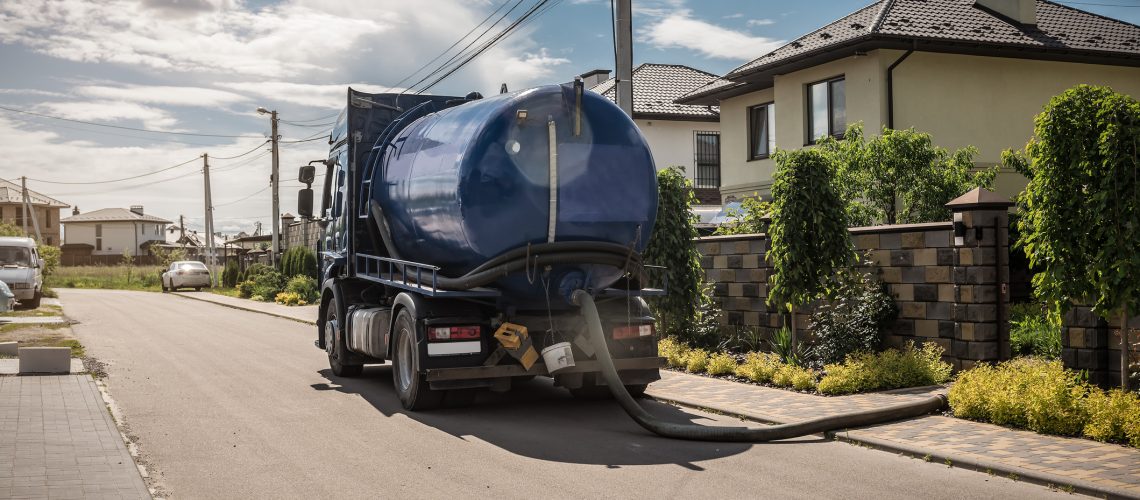 A septic truck parked outside a house that is used for septic tank pumping